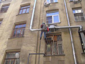climber mounts a ventilation unit outside the building